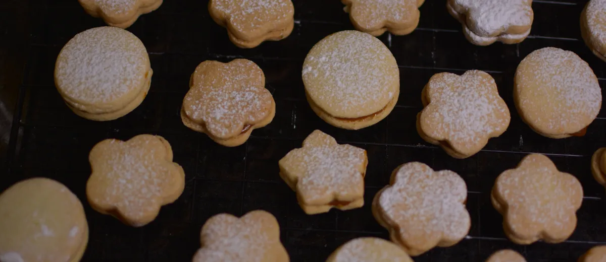 Alfajores argentins empilés, sablés pâles fourrés de dulce de leche avec les bords roulés dans la noix de coco râpée