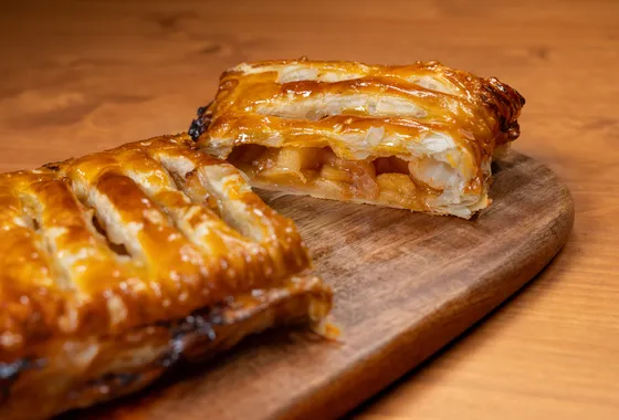 Apfelstrudel tranché, pâte fine dorée et garniture de pommes à la cannelle et raisins secs, saupoudré de sucre glace