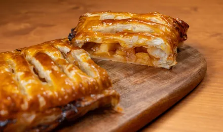 Apfelstrudel tranché, pâte fine dorée et garniture de pommes à la cannelle et raisins secs, saupoudré de sucre glace