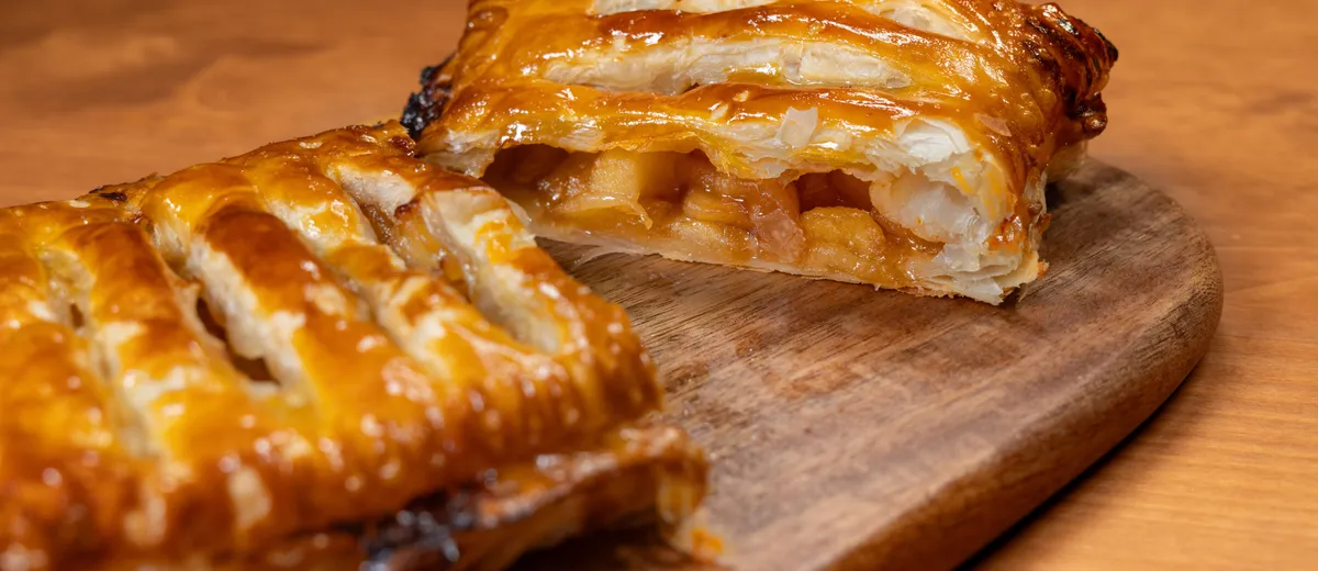 Apfelstrudel tranché, pâte fine dorée et garniture de pommes à la cannelle et raisins secs, saupoudré de sucre glace