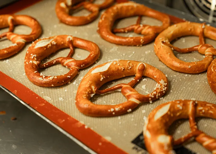 Bretzels dorés à la croûte brillante, torsadés en nœud caractéristique et parsemés de gros sel, posés sur une plaque.