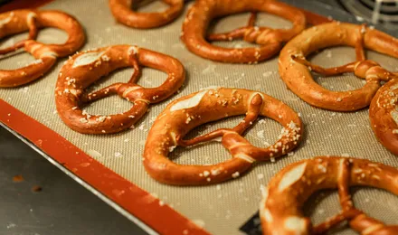 Bretzels dorés à la croûte brillante, torsadés en nœud caractéristique et parsemés de gros sel, posés sur une plaque.