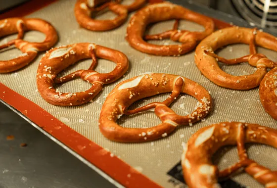 Bretzels dorés à la croûte brillante, torsadés en nœud caractéristique et parsemés de gros sel, posés sur une plaque.