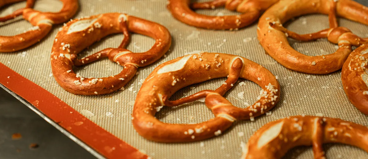 Bretzels dorés à la croûte brillante, torsadés en nœud caractéristique et parsemés de gros sel, posés sur une plaque.