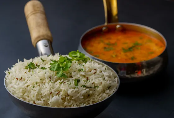 Butter chicken, poulet en sauce tomate crémeuse orange-rouge parsemée de coriandre, servi avec du riz basmati et du naan