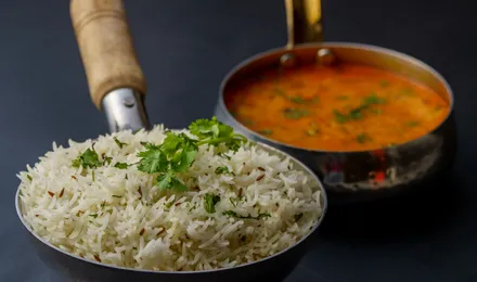 Butter chicken, poulet en sauce tomate crémeuse orange-rouge parsemée de coriandre, servi avec du riz basmati et du naan