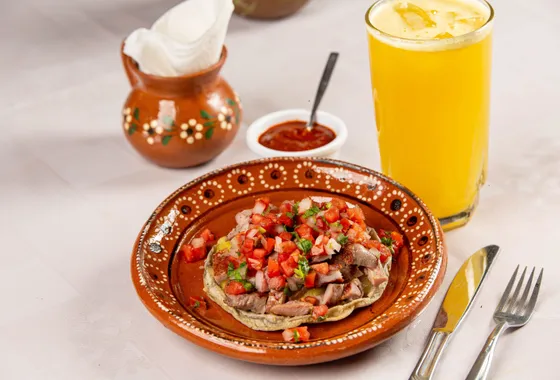 Ceviche de poisson blanc à la mexicaine dressé sur tostadas, parsemé de coriandre, dés de tomate et lamelles d'avocat.