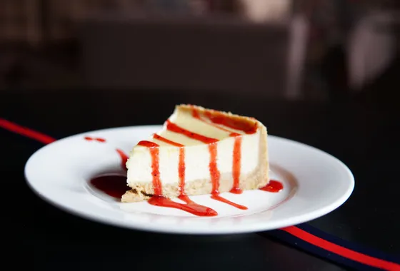 Part de New York cheesecake à la texture dense et crémeuse sur une base de biscuits sablés