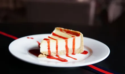 Part de New York cheesecake à la texture dense et crémeuse sur une base de biscuits sablés