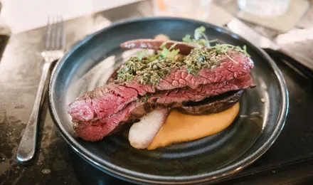 Sauce chimichurri verte dans un bol en verre, persil haché et flocons de piment liés à l'huile d'olive, à côté d'une viande grillée