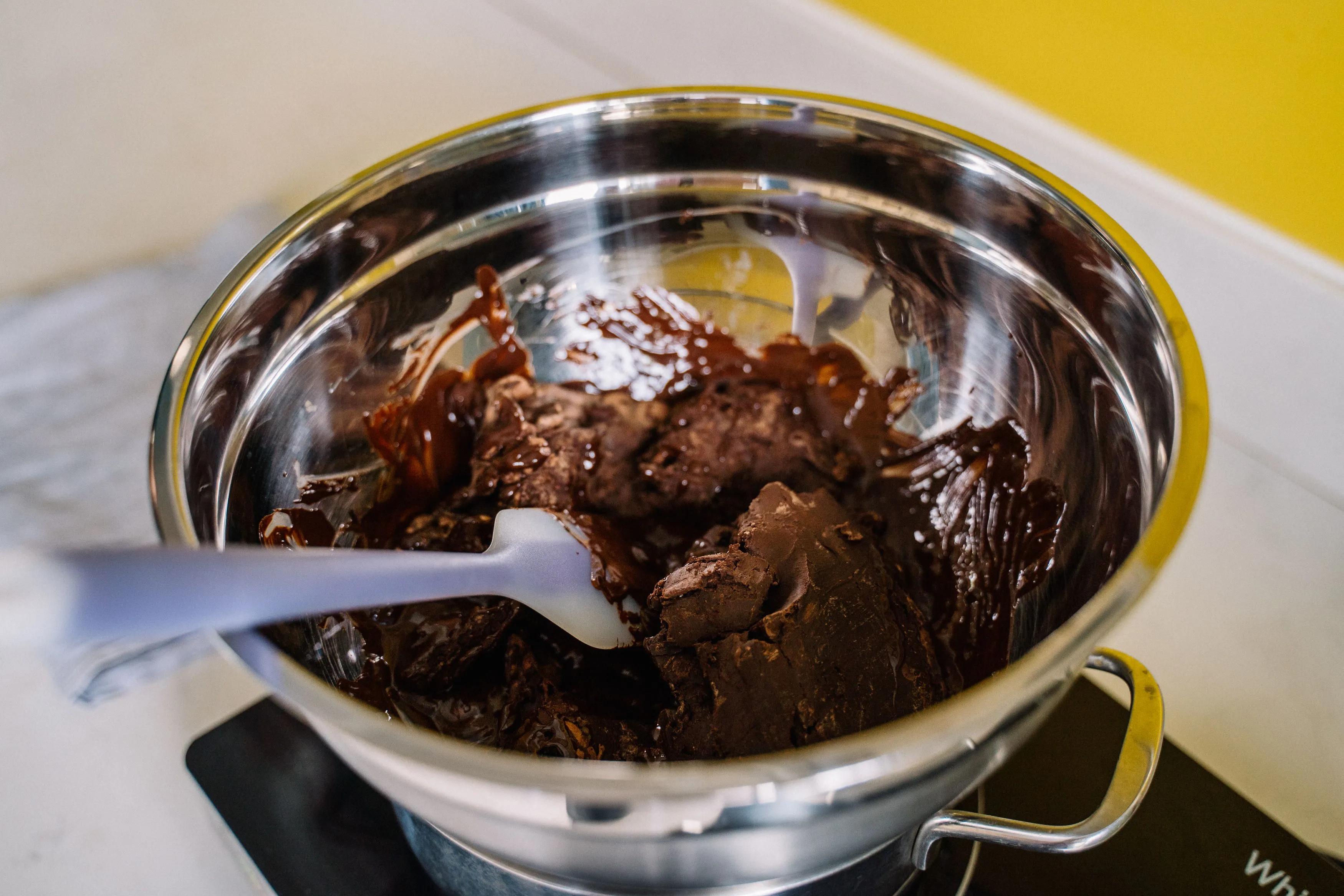 Chocolat fondu lisse et brillant dans un cul-de-poule, coulant d'une maryse