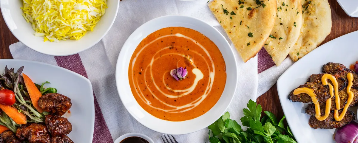 Assortiment de currys indiens colorés, riz basmati et pain naan sur une table en bois