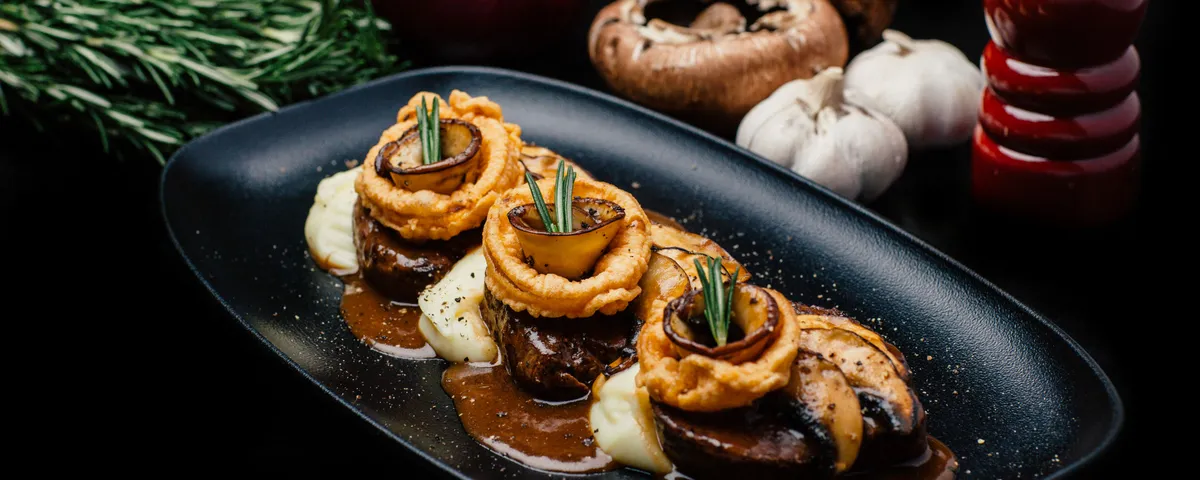 Filet de bœuf garni de rondelles d'oignon, de champignons et de romarin