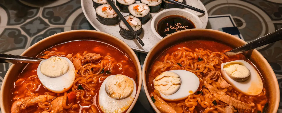 Assortiment de plats japonais traditionnels : sushi, ramen et bols de riz sur une table en bois