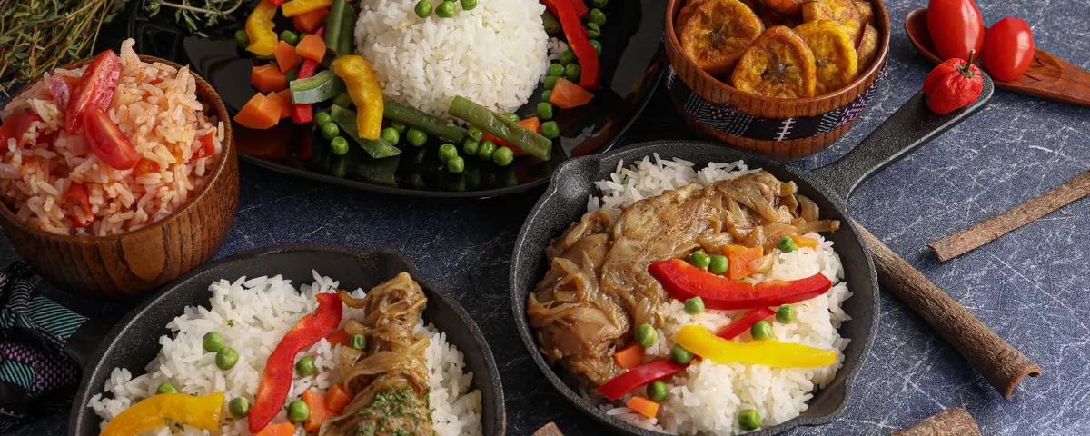 Grand plat de thiéboudienne, riz rouge au poisson et légumes fondants, posé au centre d'une table à partager