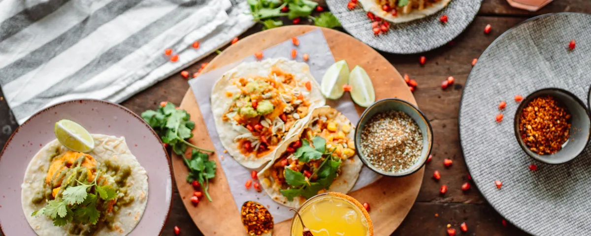 Assortiment de tacos mexicains colorés garnis de coriandre et d'oignon rouge sur une table en bois