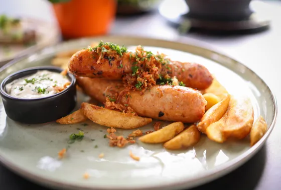 Currywurst, tronçons de saucisse grillée nappés de sauce tomate au curry et saupoudrés de poudre de curry, servis avec des frites.