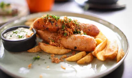 Currywurst, tronçons de saucisse grillée nappés de sauce tomate au curry et saupoudrés de poudre de curry, servis avec des frites.