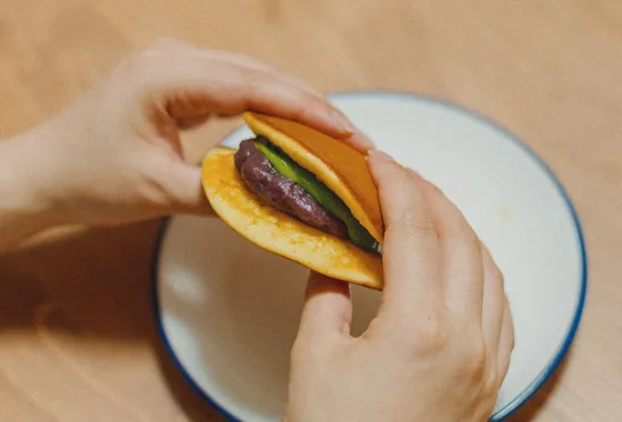 Dorayaki coupé en deux montrant la garniture d'anko brun entre deux pancakes dorés et moelleux, posés sur un plateau en bois.