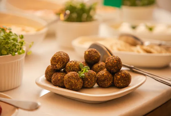 Falafels dorés croustillants sur du papier absorbant, cœur vert visible et sauce tahini à côté