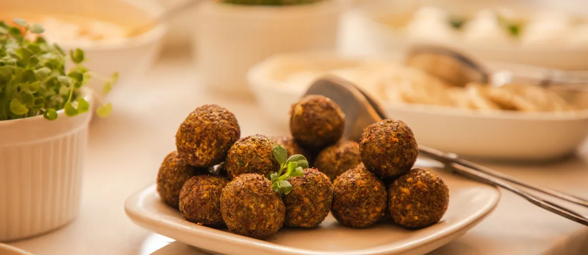 Falafels dorés croustillants sur du papier absorbant, cœur vert visible et sauce tahini à côté