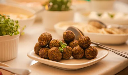 Falafels dorés croustillants sur du papier absorbant, cœur vert visible et sauce tahini à côté