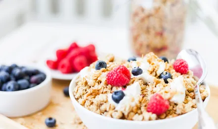 Granola maison croustillant en pépites dorées, amandes, noix, graines de courge et cranberries, dans un bol