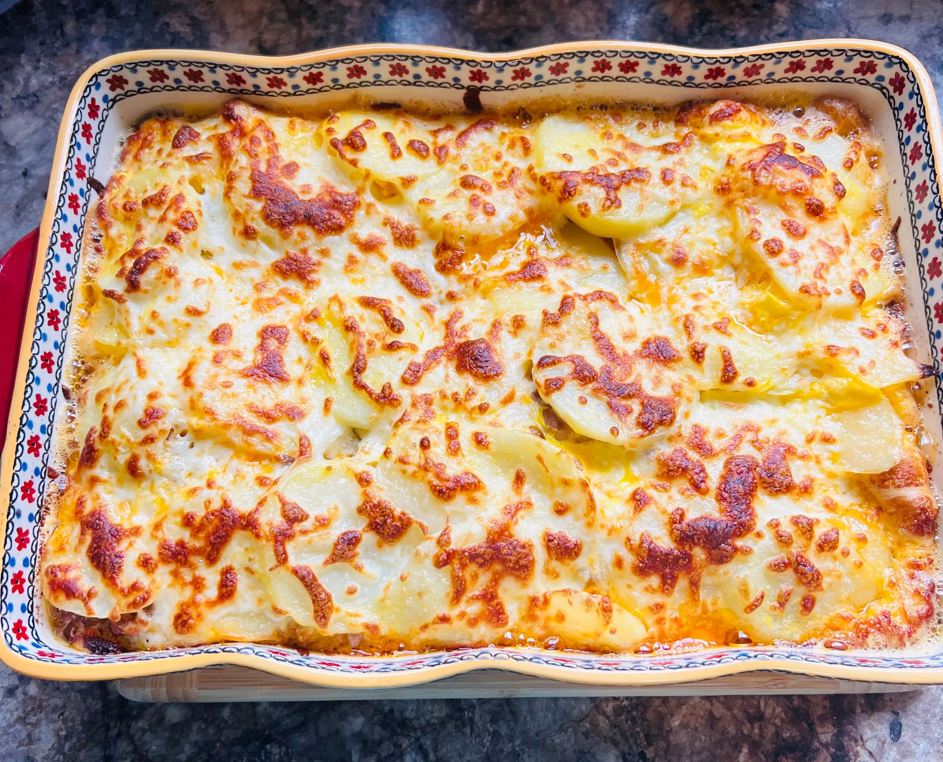 Gratin dauphinois doré dans un plat en céramique, une part découpée nette