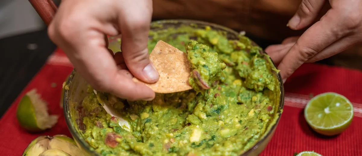 Guacamole maison servi dans un bol, avocat écrasé grossièrement parsemé de coriandre et de dés de tomate