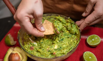 Guacamole maison servi dans un bol, avocat écrasé grossièrement parsemé de coriandre et de dés de tomate