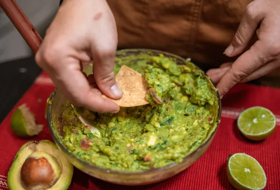 Guacamole maison servi dans un bol, avocat écrasé grossièrement parsemé de coriandre et de dés de tomate