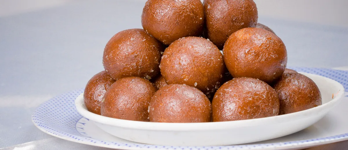 Gulab jamun dorés baignant dans leur sirop ambré parfumé, garnis de pistaches concassées