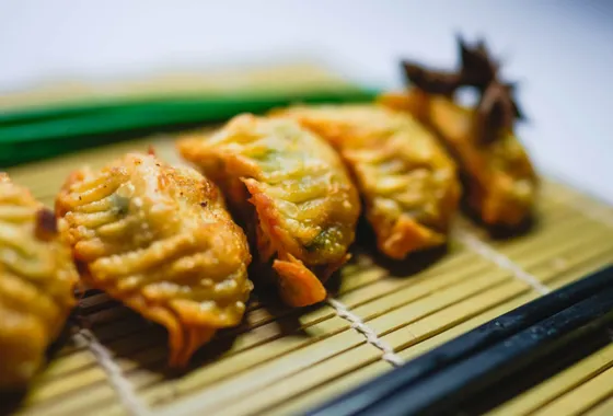 Gyoza japonais dorés à la poêle, alignés en arc de cercle, servis avec un petit bol de sauce soja vinaigrée.