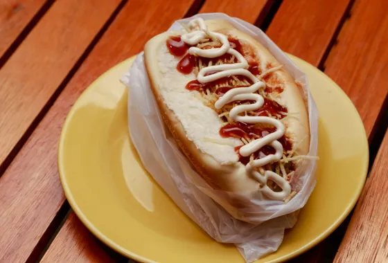 Hot dog garni de saucisse fumée, moutarde, ketchup et oignons dans un pain allongé toasté