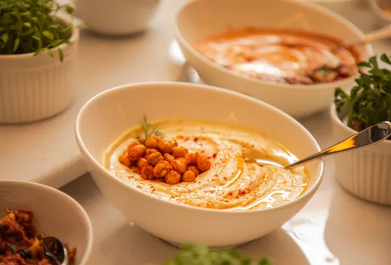 Bol de houmous crémeux nappé d'huile d'olive, saupoudré de paprika et parsemé de pois chiches
