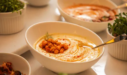 Bol de houmous crémeux nappé d'huile d'olive, saupoudré de paprika et parsemé de pois chiches