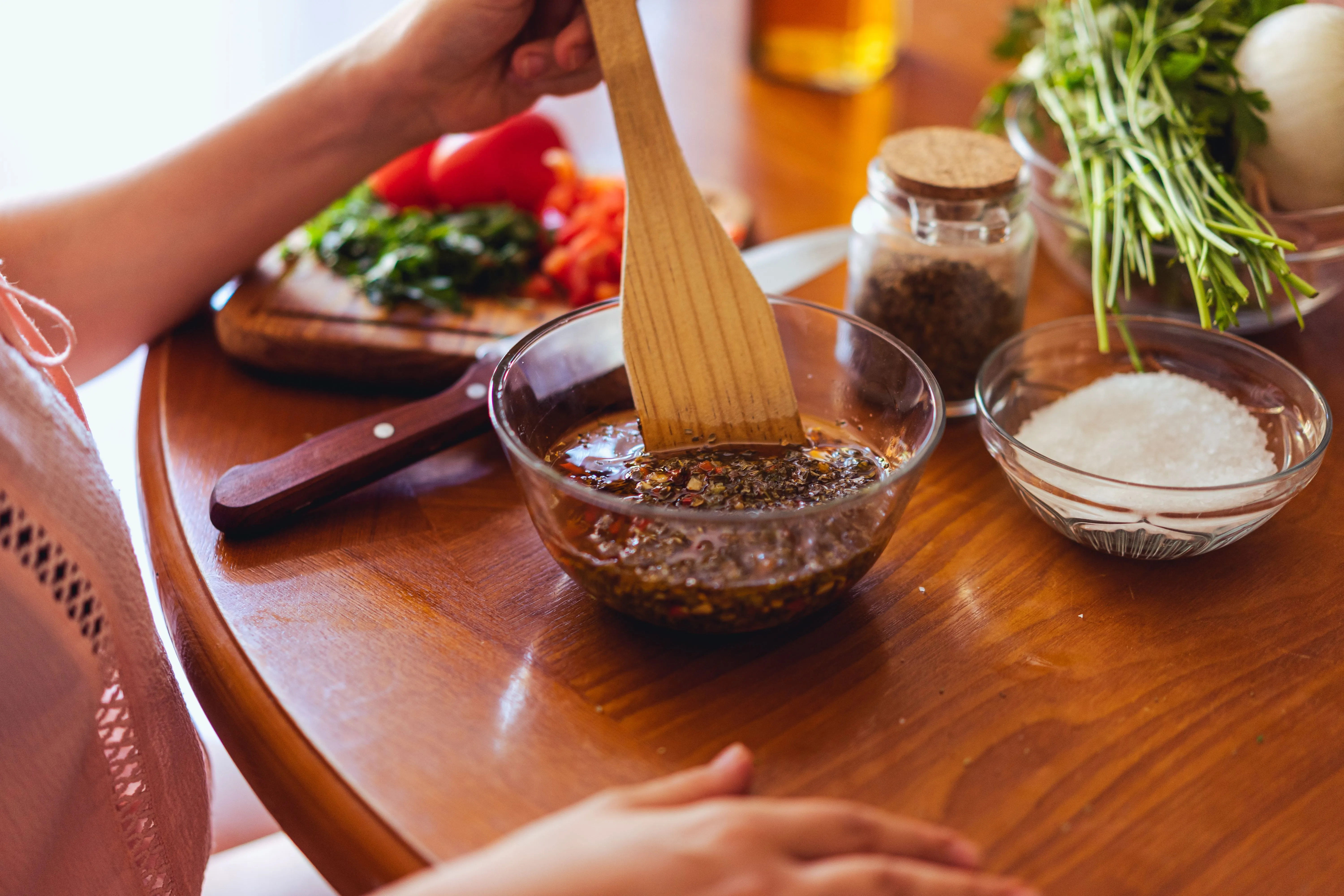 Persil plat, gousses d'ail, origan séché, gros sel, pot de dulce de leche et yerba maté disposés sur un plan de travail en bois
