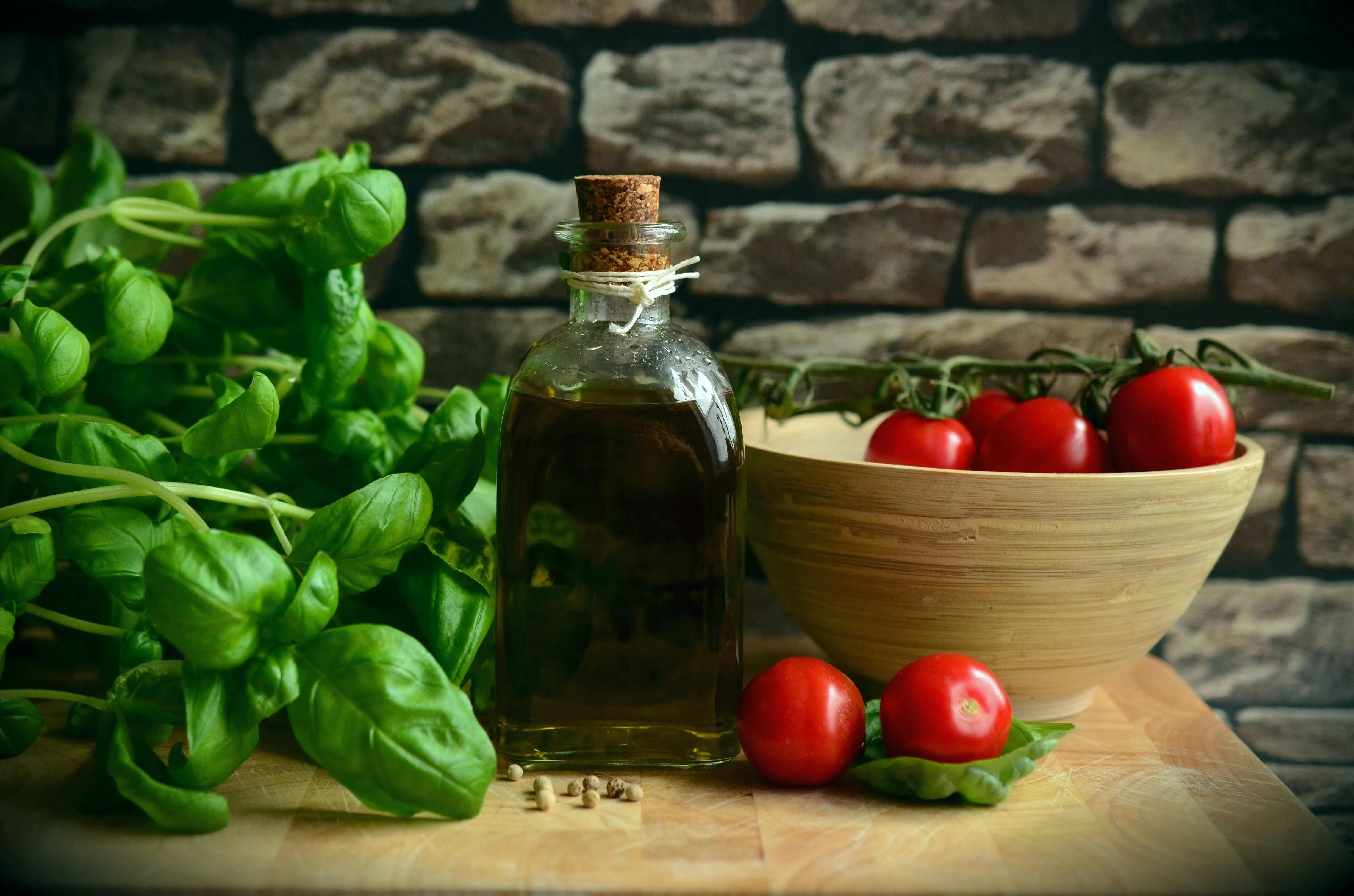 Huile d'olive, tomates, parmesan et basilic frais disposés sur une table en bois, ingrédients emblématiques de la cuisine italienne