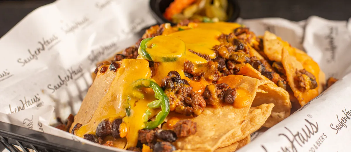 Plateau de nachos gratinés au cheddar fondant, garnis de bœuf haché, jalapeños, guacamole et crème fraîche