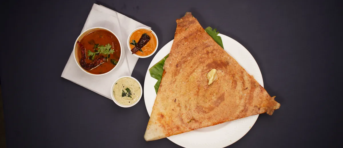 Masala dosa dorée et croustillante roulée sur une garniture de pommes de terre épicées, servie avec chutney à la noix de coco