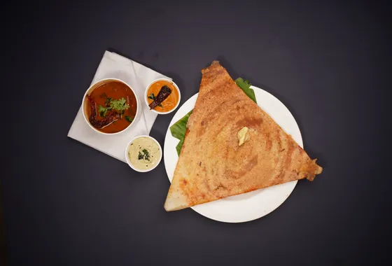 Masala dosa dorée et croustillante roulée sur une garniture de pommes de terre épicées, servie avec chutney à la noix de coco