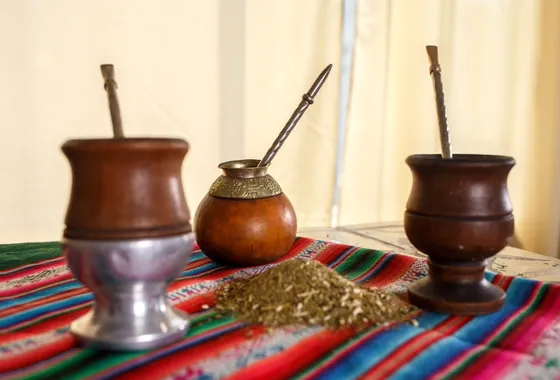 Calebasse de maté remplie de yerba verte avec une bombilla métallique, posée sur une table en bois à côté d'un thermos