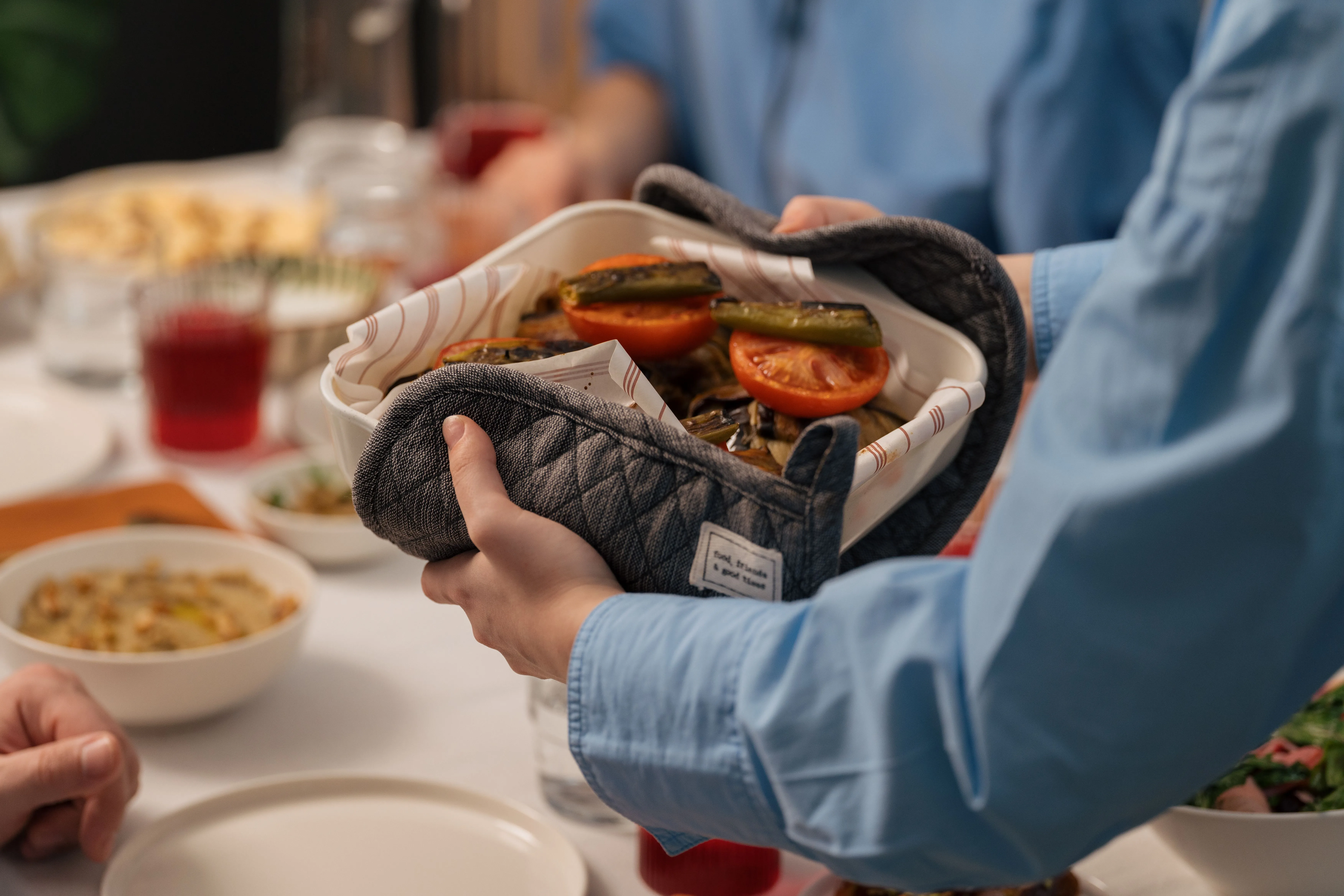 Cocotte de mijoté posée au centre d'une table familiale, mains qui se servent