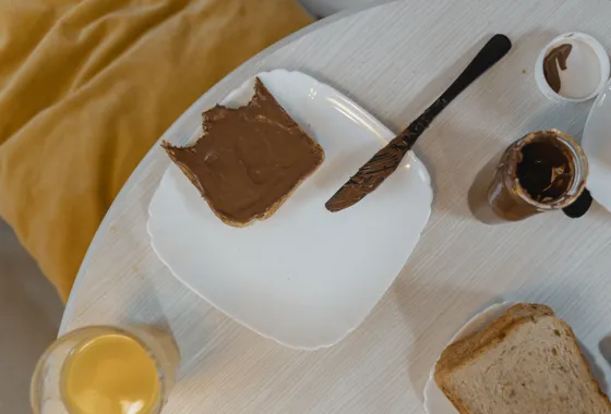 Pot de pâte à tartiner maison au chocolat et à la noisette, texture lisse et brillante, cuillère plongée dedans