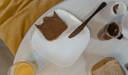 Pot de pâte à tartiner maison au chocolat et à la noisette, texture lisse et brillante, cuillère plongée dedans
