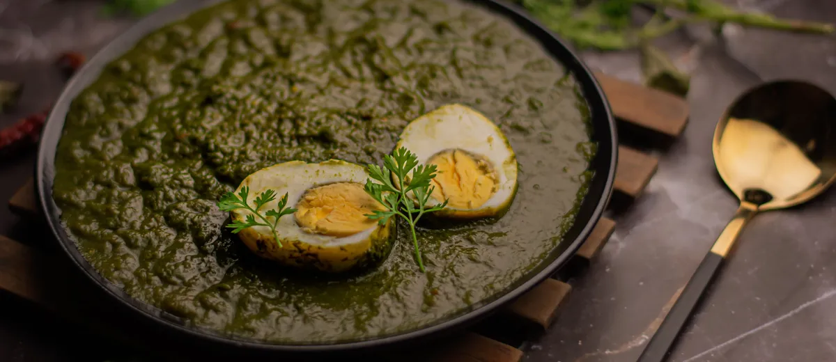 Palak paneer, cubes de fromage indien dans une sauce d'épinards vert profond parsemée de crème, servi avec du naan