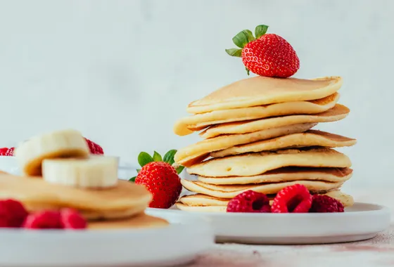 Pile de pancakes moelleux et dorés nappés de sirop d'érable avec une noix de beurre fondant