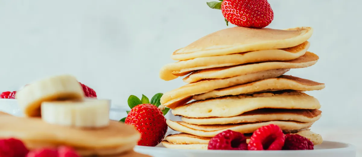 Pile de pancakes moelleux et dorés nappés de sirop d'érable avec une noix de beurre fondant