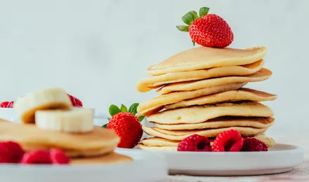 Pile de pancakes moelleux et dorés nappés de sirop d'érable avec une noix de beurre fondant
