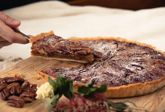 Pecan pie dorée aux noix de pécan caramélisées, une part coupée révélant l'appareil ambré et fondant